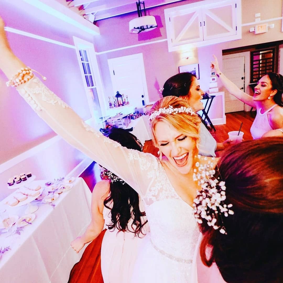 Bride celebrating with guests at wedding reception with pink uplighting